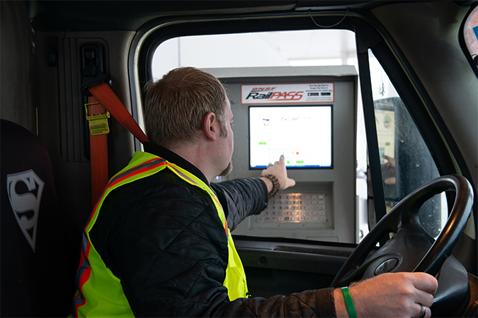 A truck driver uses a kiosk at the entrance to a BNSF intermodal facility. A truck driver uses a kiosk at the entrance to a BNSF intermodal facility.