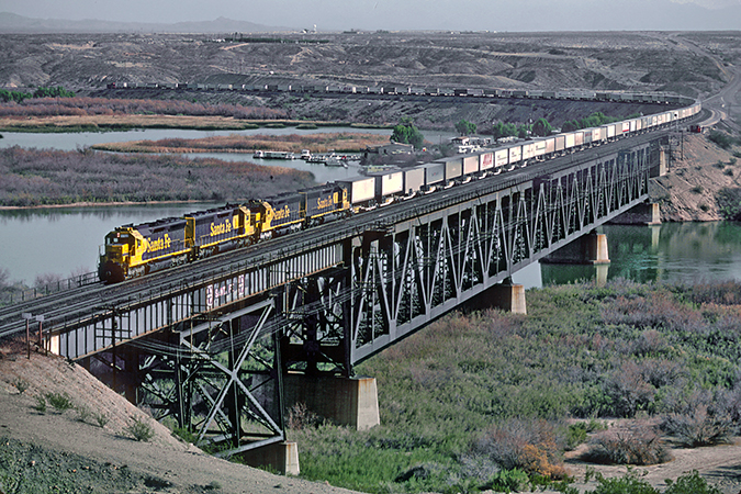 A Santa Fe “piggyback” or TOFC train crosses the Arizona-California border on the Colorado River Bridge in January 1983. A Santa Fe “piggyback” or TOFC train crosses the Arizona-California border on the Colorado River Bridge in January 1983.
