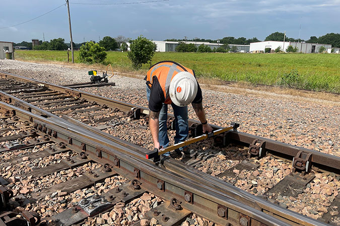 Cunningham measuring the distance between the rails using a track gauge